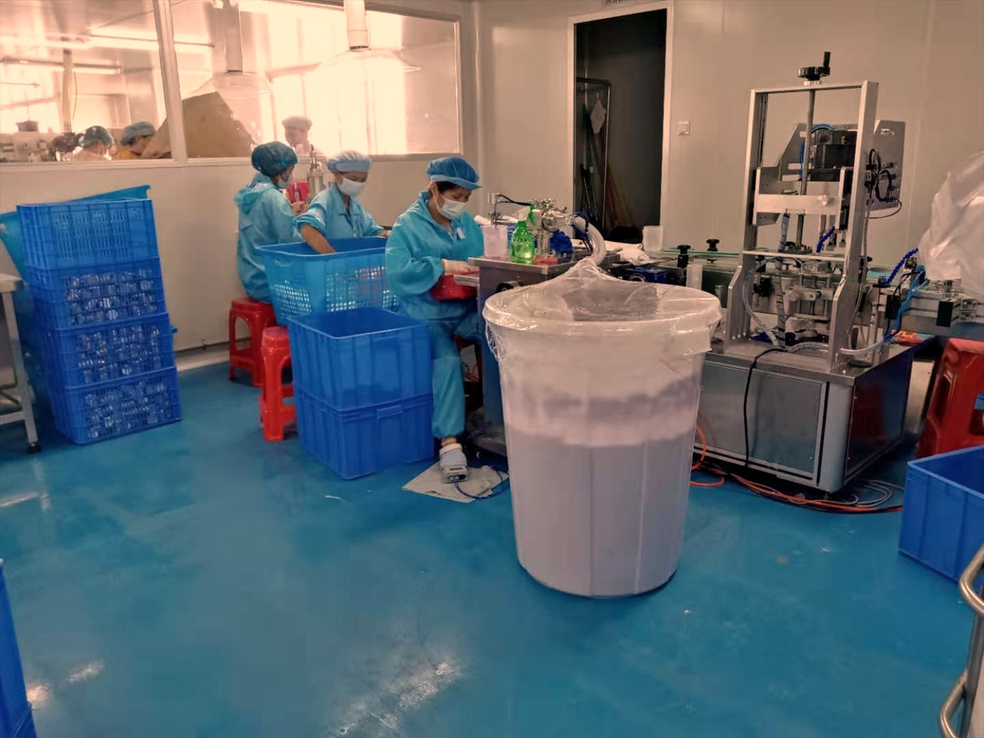 Operators in cleanroom dress at the filling bench inside the production workshop